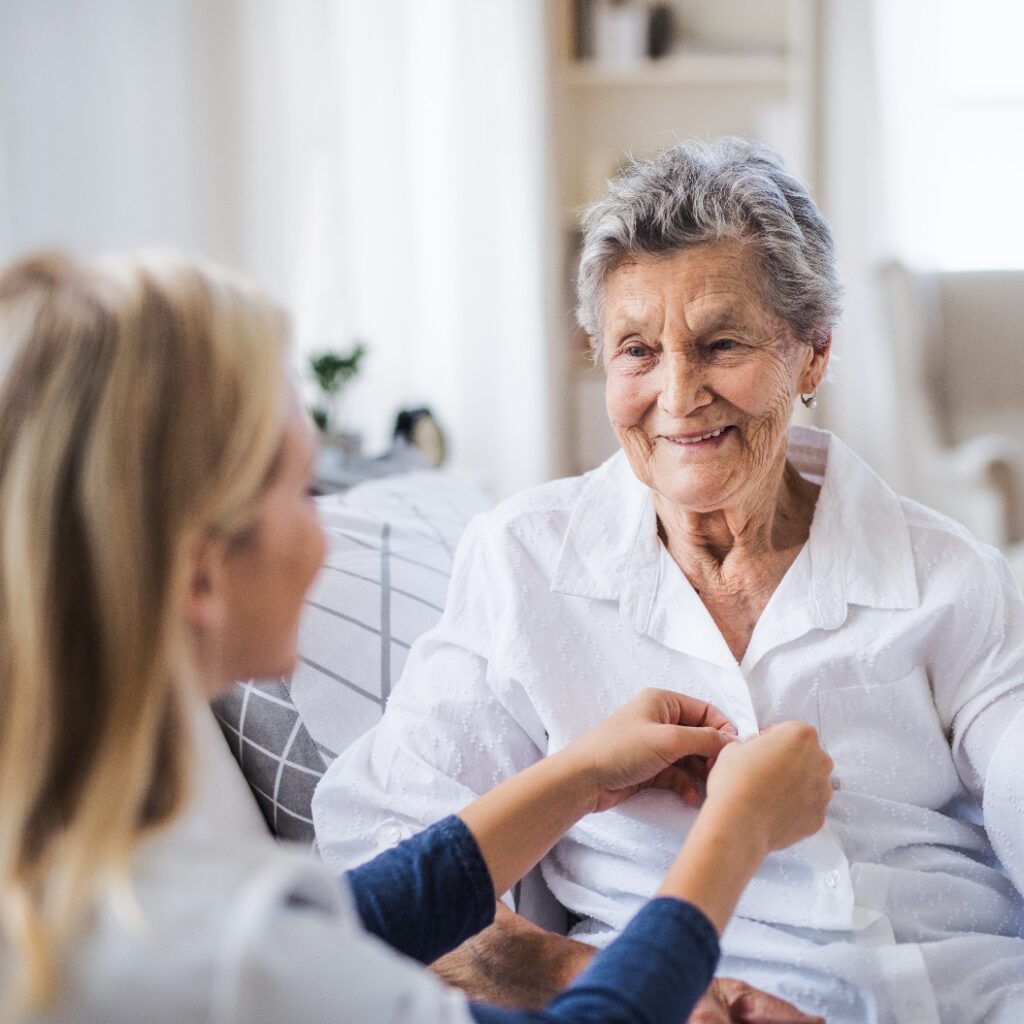 Eine Gesundheitsberaterin hilft einer kranken älteren Frau, die zu Hause im Bett sitzt.
