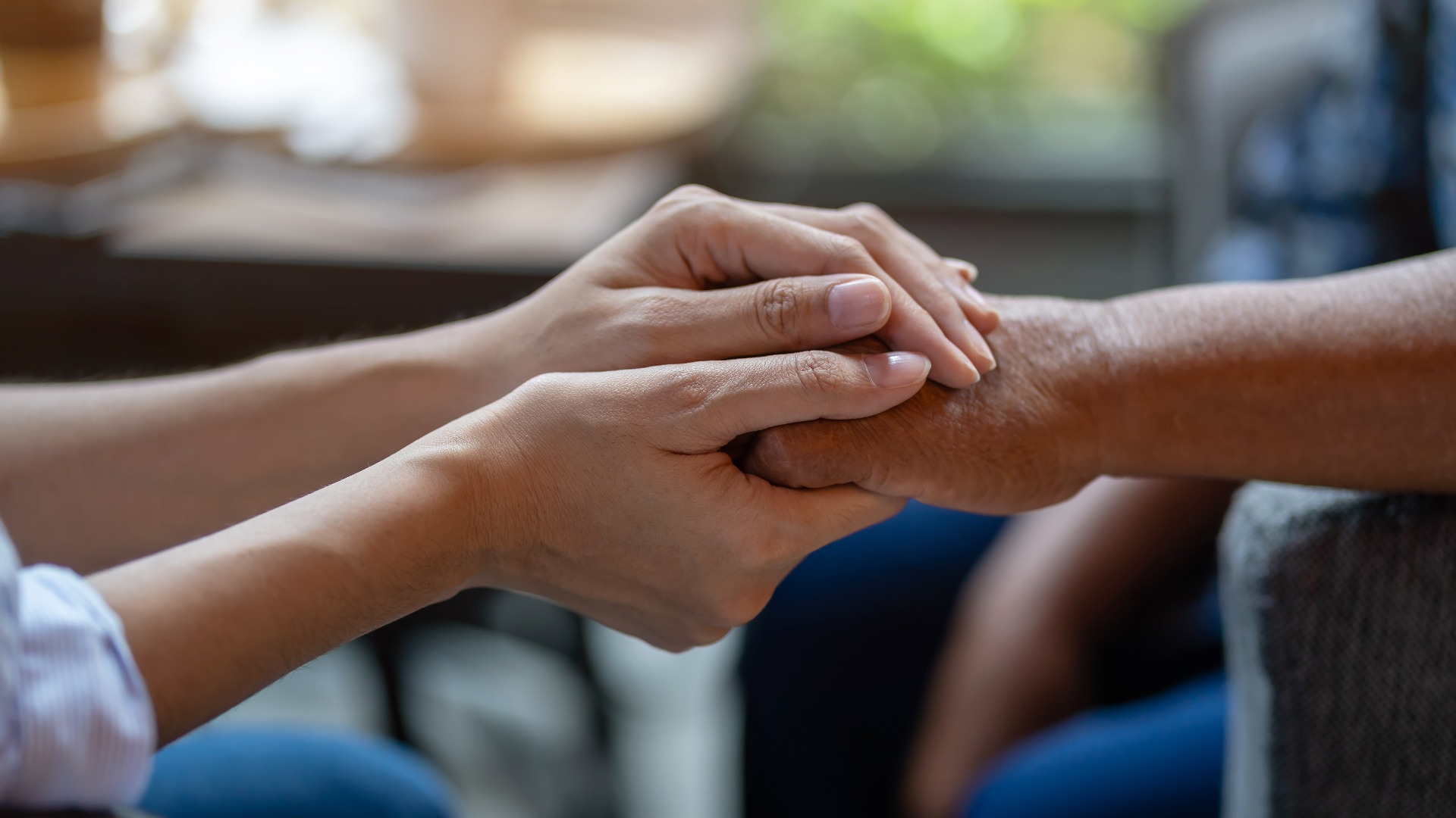 Die Hand einer jüngeren Frau, die die Hand einer älteren Frau hält, Hilfsbereite Hände,